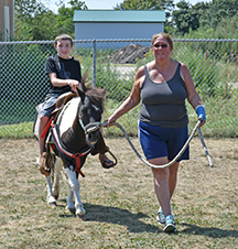 Darlene Silva of Annie Hill Farm in Fairhaven gives Kalib a ride on Buck at the Fairhaven Animal Shelter open house on Saturday, 8/20. Photo by Beth David.