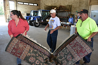 Public Works employee Manny Souza (RIGHT) helps Stephanie Nolan and George Paulino with the carpet they bought at the Fairhaven town auction on Saturday, 9/17.
