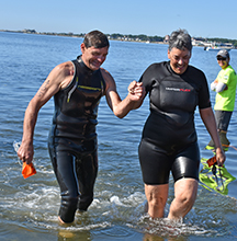 Gerry Payette, 64, of Bristol, RI, and his cousin Gisele Pappas, 60, of New Bedford, hold hands as the last two out of the water, crossing the finish line together in 1:24:15.  Photo by Beth David.